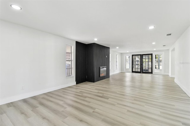 unfurnished living room with light wood-type flooring and french doors