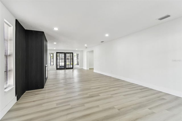 unfurnished living room with french doors and light wood-type flooring