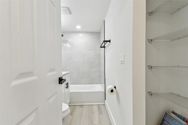 bathroom featuring hardwood / wood-style floors, toilet, and tiled shower / bath