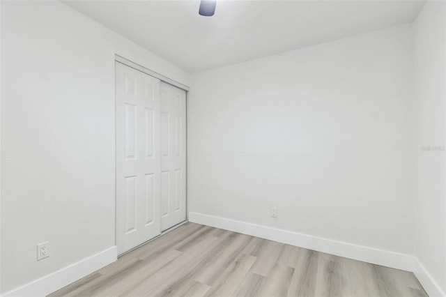 unfurnished bedroom featuring ceiling fan, light hardwood / wood-style floors, and a closet