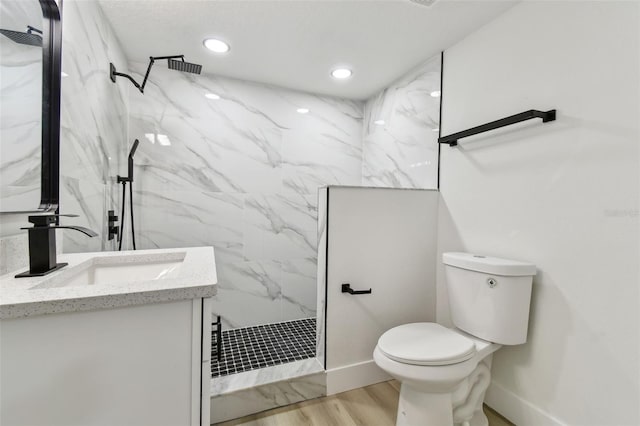 bathroom featuring tiled shower, hardwood / wood-style floors, vanity, and toilet