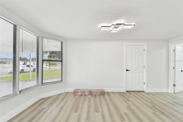 empty room with a textured ceiling and light wood-type flooring