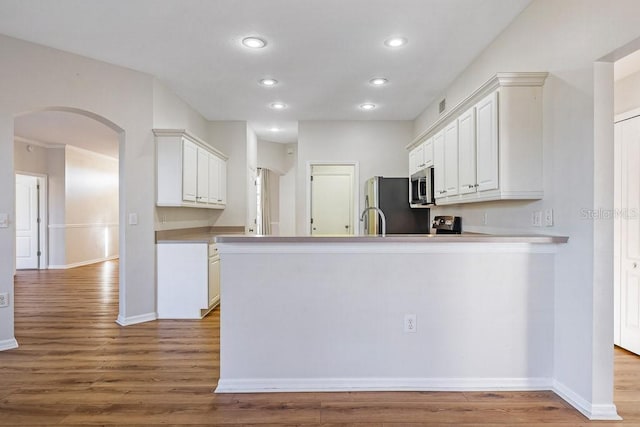 kitchen with kitchen peninsula, appliances with stainless steel finishes, light hardwood / wood-style floors, and white cabinetry