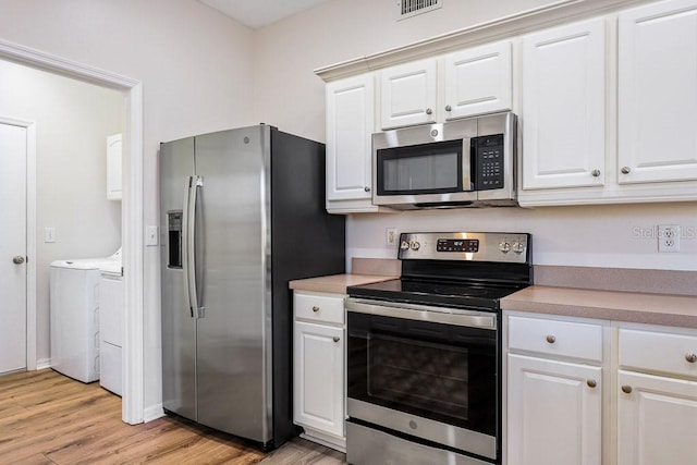 kitchen featuring white cabinets, stainless steel appliances, separate washer and dryer, and light hardwood / wood-style flooring