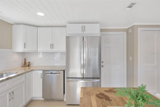 kitchen featuring backsplash, light stone counters, stainless steel appliances, crown molding, and white cabinets