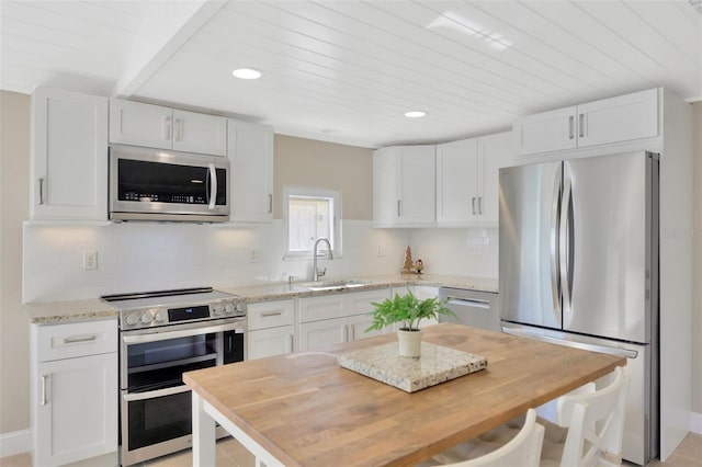 kitchen featuring white cabinetry, sink, light stone countertops, decorative backsplash, and appliances with stainless steel finishes