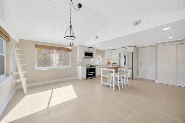 kitchen featuring stainless steel appliances, a kitchen island, decorative light fixtures, a breakfast bar area, and white cabinets