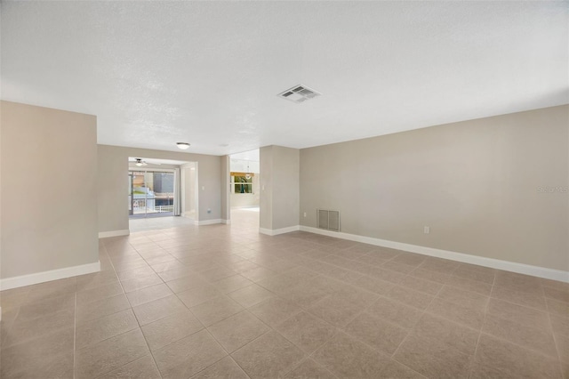 tiled empty room with a textured ceiling