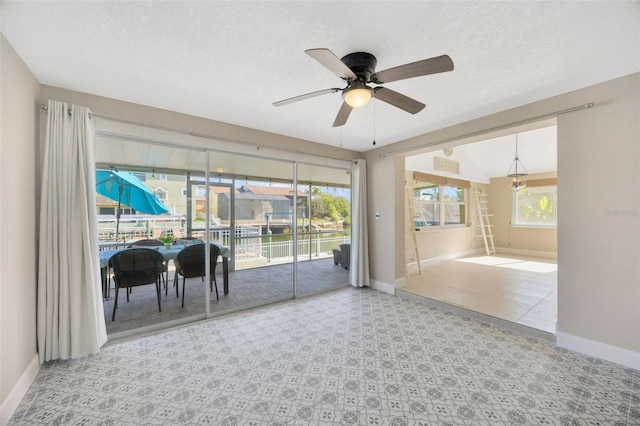 unfurnished room with ceiling fan with notable chandelier and a textured ceiling