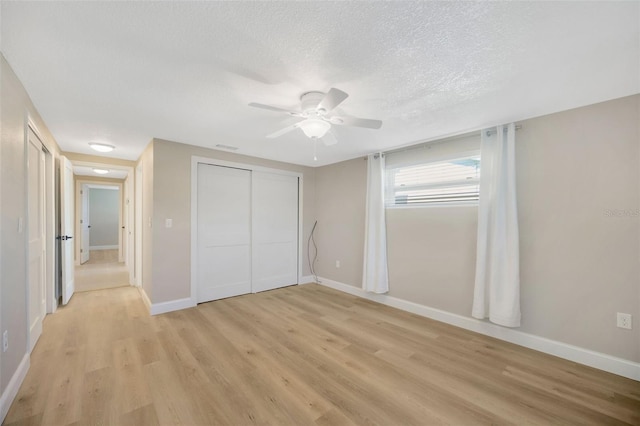 unfurnished bedroom featuring ceiling fan, a closet, light hardwood / wood-style floors, and a textured ceiling