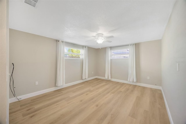 unfurnished room with a textured ceiling, light wood-type flooring, and ceiling fan