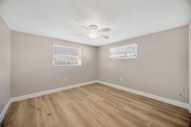 empty room featuring a textured ceiling, light hardwood / wood-style floors, and a wealth of natural light