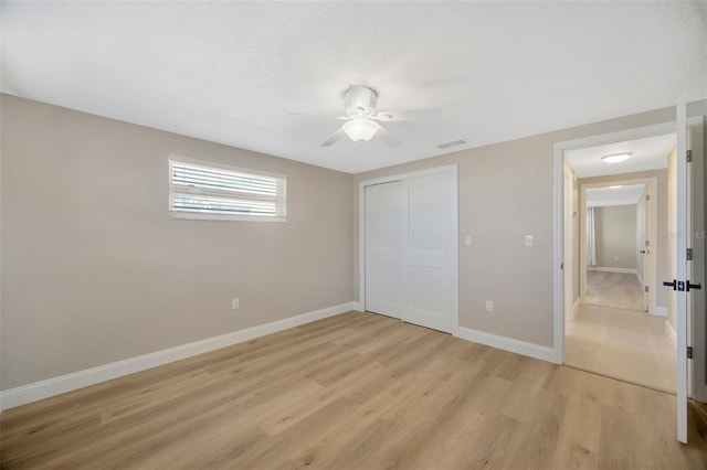 unfurnished bedroom featuring ceiling fan, a closet, and light hardwood / wood-style floors