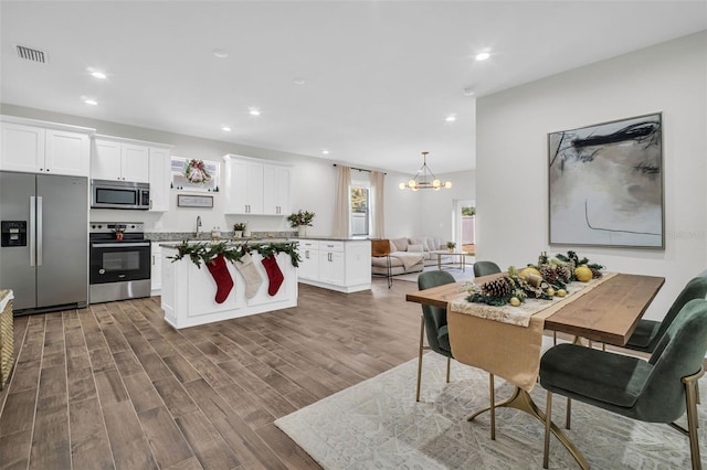 kitchen featuring hanging light fixtures, stainless steel appliances, dark hardwood / wood-style flooring, a notable chandelier, and white cabinets