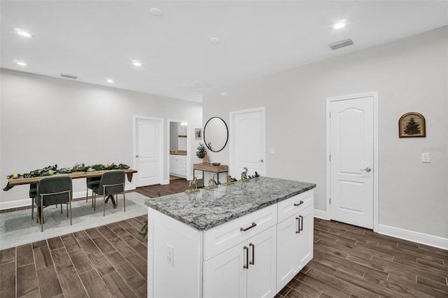 kitchen featuring a center island, dark hardwood / wood-style flooring, and light stone countertops