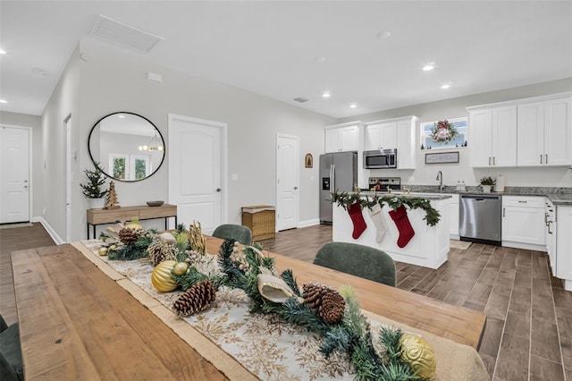 kitchen with white cabinets, appliances with stainless steel finishes, dark hardwood / wood-style flooring, and a kitchen island