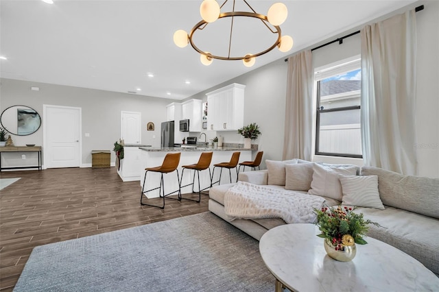 living room with dark hardwood / wood-style flooring, an inviting chandelier, and sink