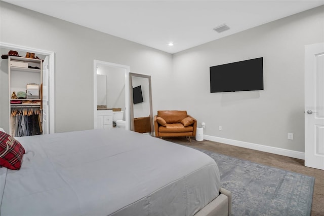 carpeted bedroom featuring a walk in closet, ensuite bath, and a closet