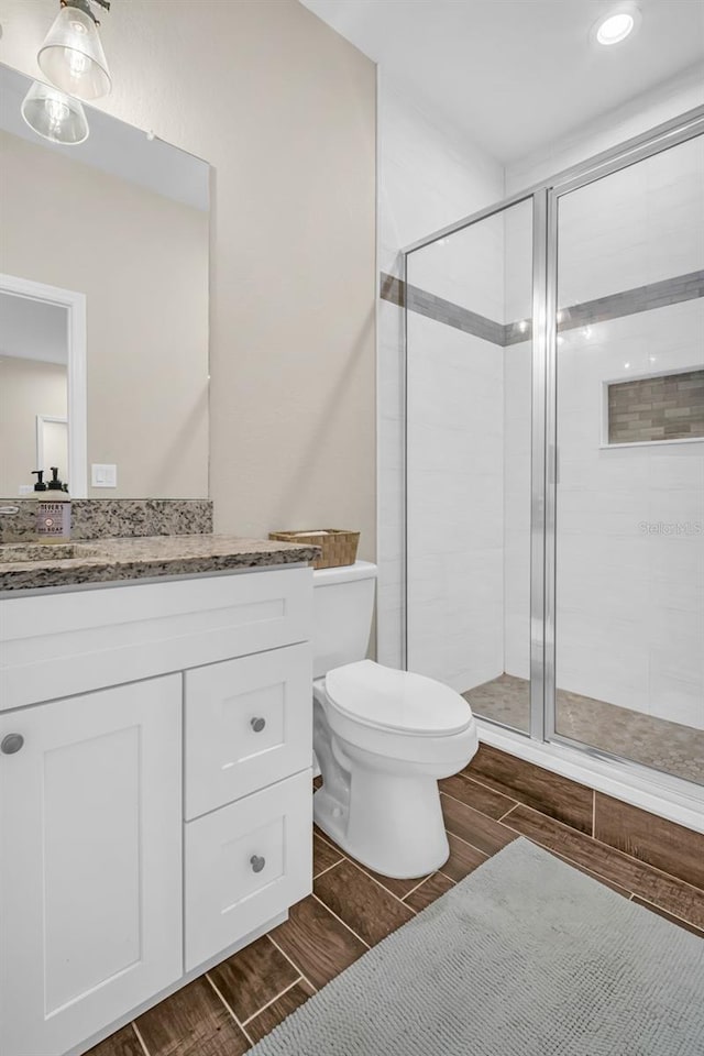 bathroom with vanity, toilet, and a shower with door