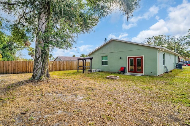 rear view of house featuring a lawn, french doors, and an outdoor fire pit