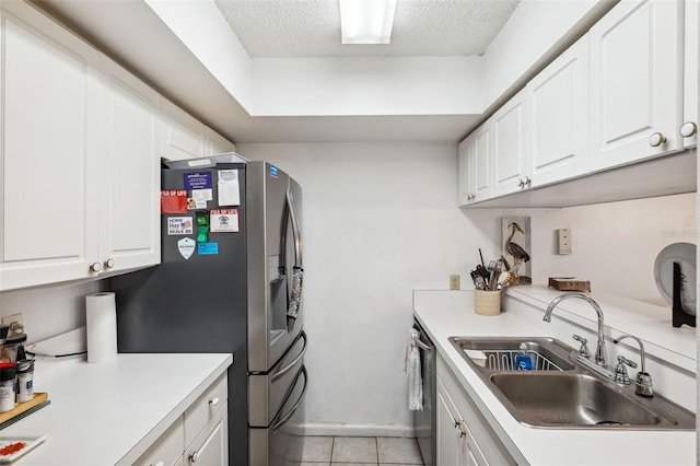 kitchen with sink, light tile patterned floors, a textured ceiling, white cabinets, and appliances with stainless steel finishes