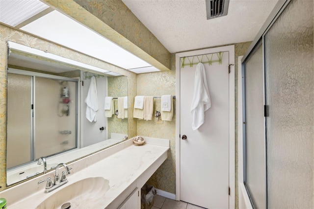 bathroom featuring tile patterned flooring, vanity, a shower with door, and a textured ceiling