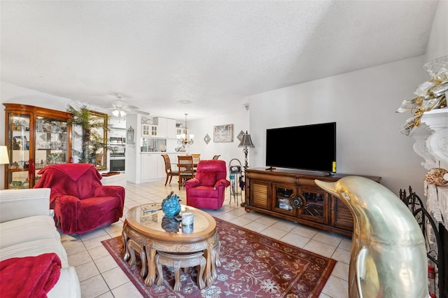 tiled living room featuring a textured ceiling and ceiling fan with notable chandelier