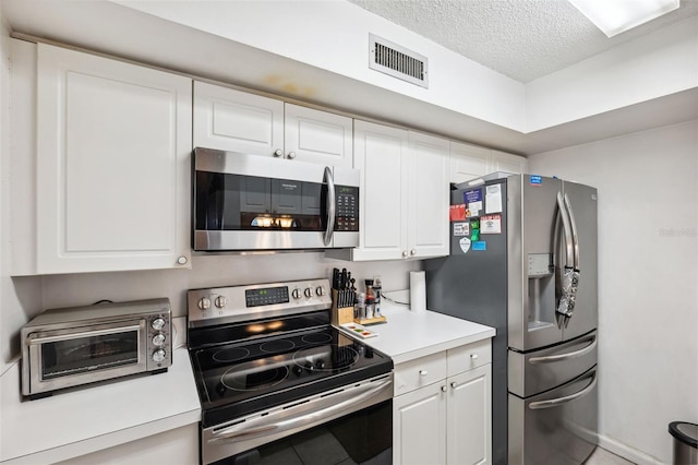 kitchen featuring white cabinets, stainless steel appliances, and a textured ceiling