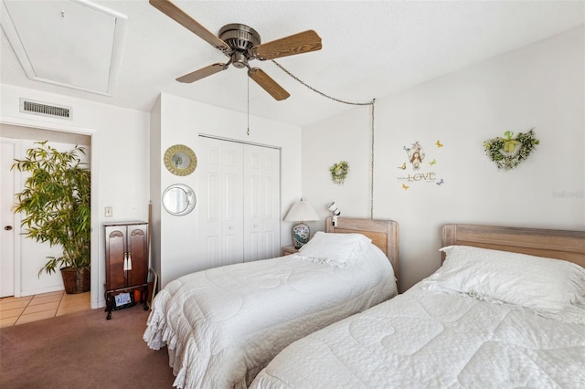 carpeted bedroom with ceiling fan, a closet, and a textured ceiling