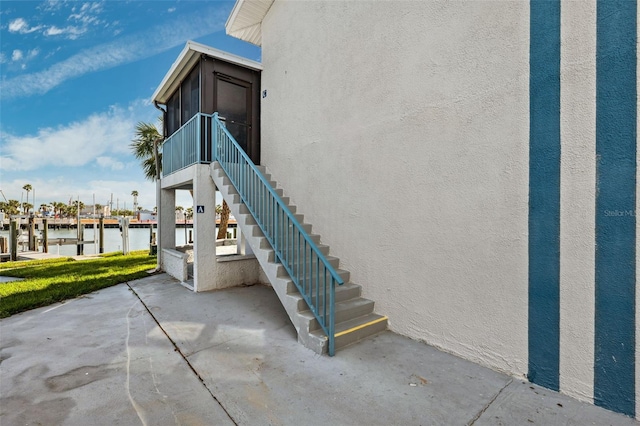 exterior space featuring a sunroom, a patio area, and a water view