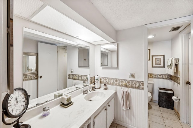 bathroom featuring vanity, electric panel, tile patterned floors, toilet, and a textured ceiling