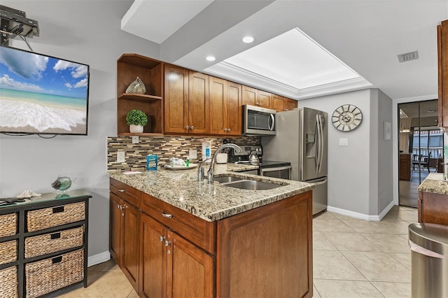 kitchen featuring appliances with stainless steel finishes, light stone countertops, sink, and backsplash