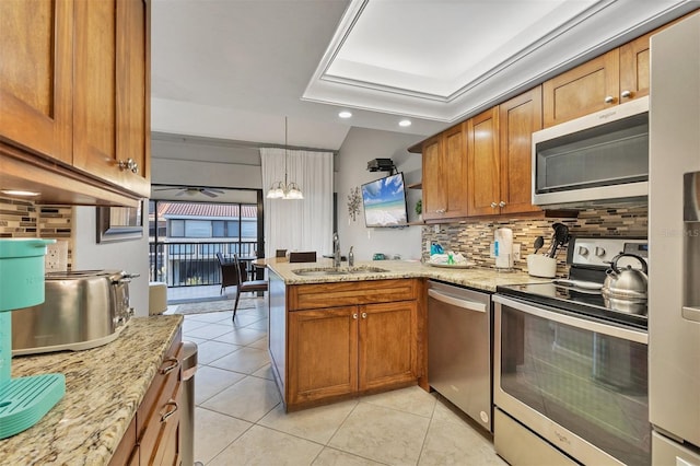 kitchen featuring sink, hanging light fixtures, light tile patterned floors, appliances with stainless steel finishes, and kitchen peninsula