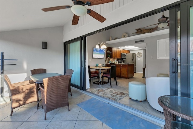 tiled dining space featuring ceiling fan, lofted ceiling, and sink