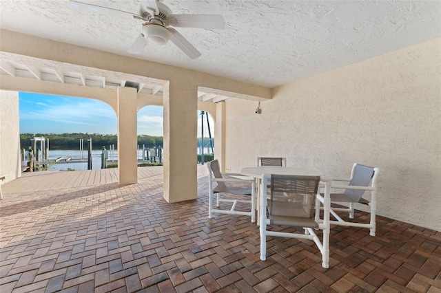 view of patio featuring ceiling fan, a water view, and a boat dock