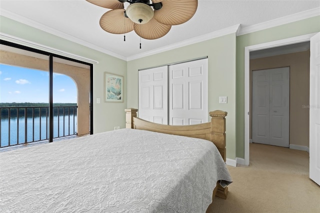 carpeted bedroom with ornamental molding, access to outside, ceiling fan, a water view, and a closet