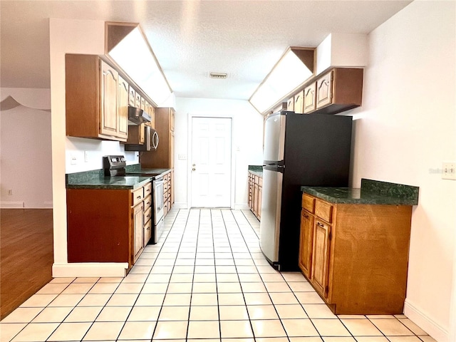 kitchen with light tile patterned floors, stainless steel appliances, and a textured ceiling