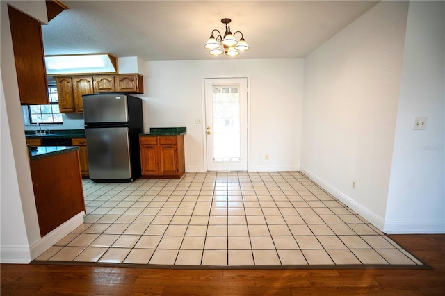 kitchen with a chandelier, stainless steel fridge, a wealth of natural light, and sink