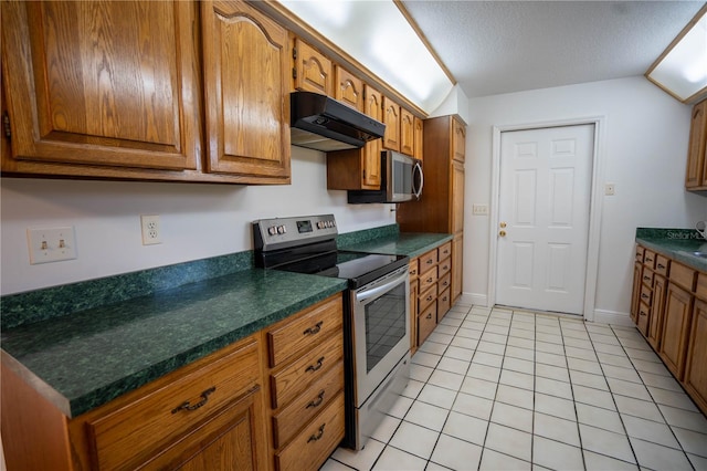 kitchen with light tile patterned floors, a textured ceiling, and stainless steel appliances