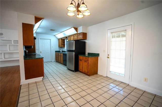 kitchen with black dishwasher, an inviting chandelier, stainless steel fridge, a textured ceiling, and light tile patterned flooring