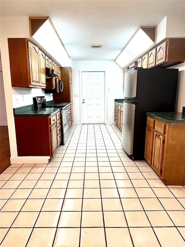 kitchen featuring light tile patterned flooring, a textured ceiling, and appliances with stainless steel finishes