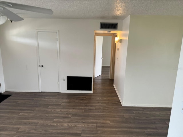 empty room with ceiling fan, dark hardwood / wood-style flooring, and a textured ceiling