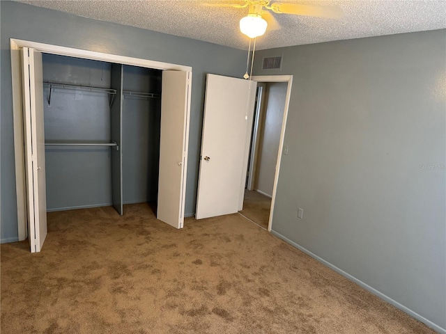 unfurnished bedroom featuring carpet, a textured ceiling, a closet, and ceiling fan