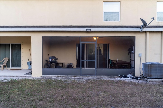 rear view of house with central AC unit and a sunroom