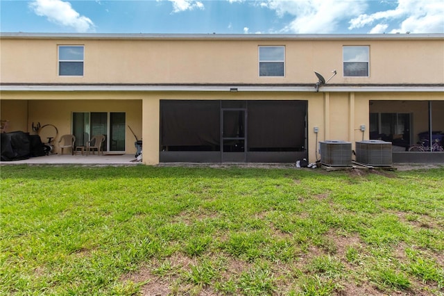 12827 Buffalo Run Dr, Gibsonton, FL 33534 - rear view of house with stucco siding, central AC unit, a patio, and a lawn