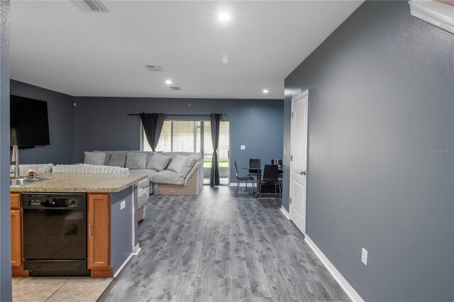 12827 Buffalo Run Dr, Gibsonton, FL 33534 - kitchen with black dishwasher, a sink, brown cabinets, light countertops, and light wood finished floors