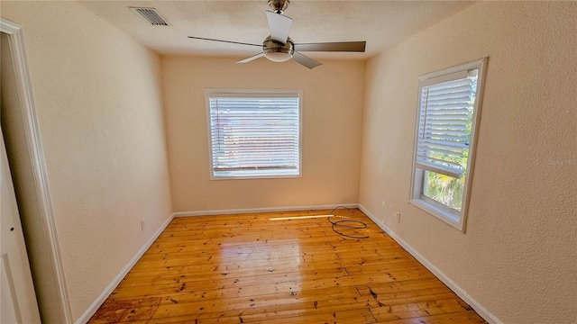 empty room with ceiling fan, a textured ceiling, and light wood-type flooring