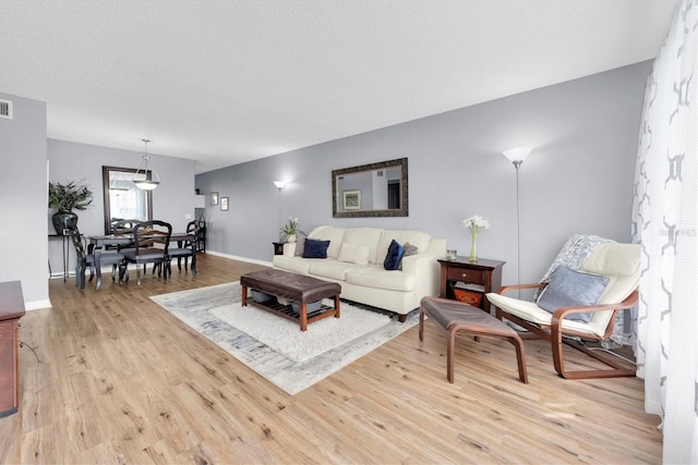 living room with light wood-type flooring and a textured ceiling