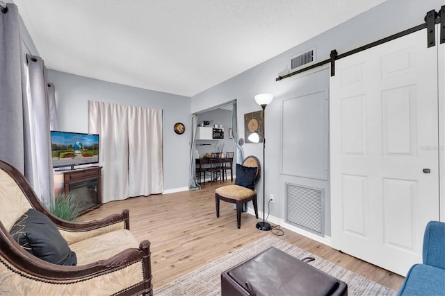 living room with light hardwood / wood-style floors, a barn door, and a fireplace