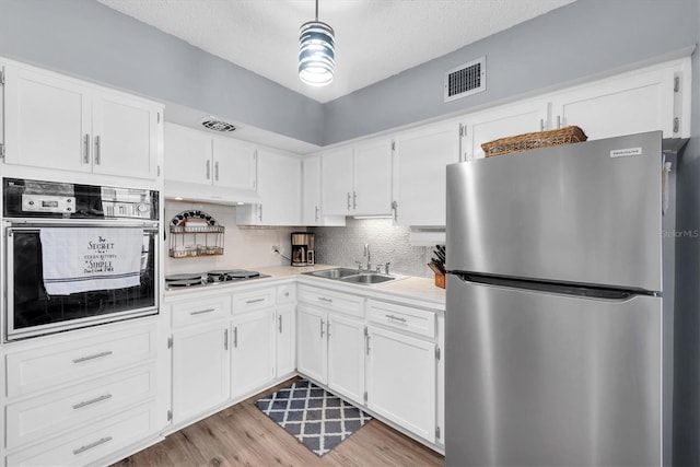 kitchen featuring stainless steel fridge, sink, oven, light hardwood / wood-style floors, and white cabinetry